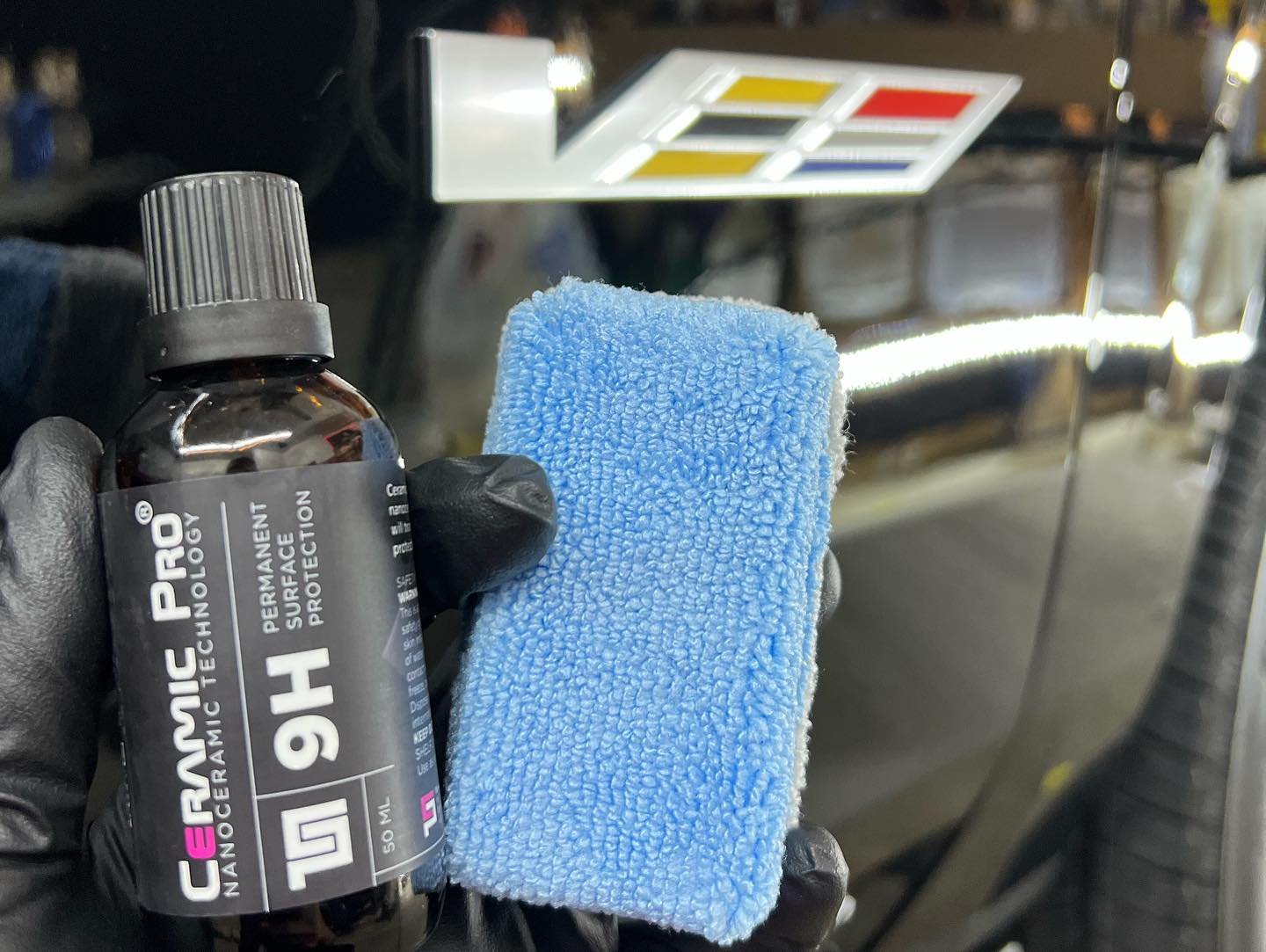 Holding Ceramic Pro ceramic coating bottle and sponge, before application on SUV in Washington, MI